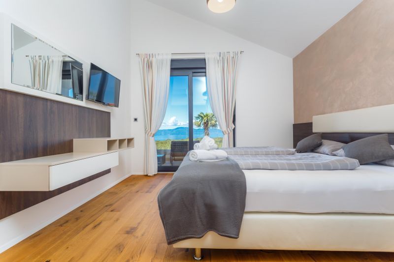 Ferienvilla mit Pool in Kroatien, Schlafzimmer mit grauer Bettwäsche und Fernseher und Ausgang zur Terrasse