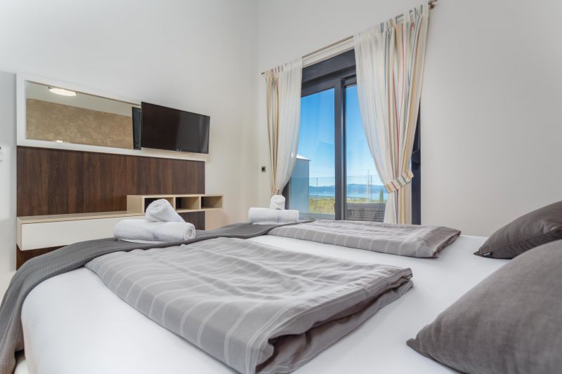 Holiday villa with pool in Croatia, bedroom with gray bedding and television and exit to the terrace