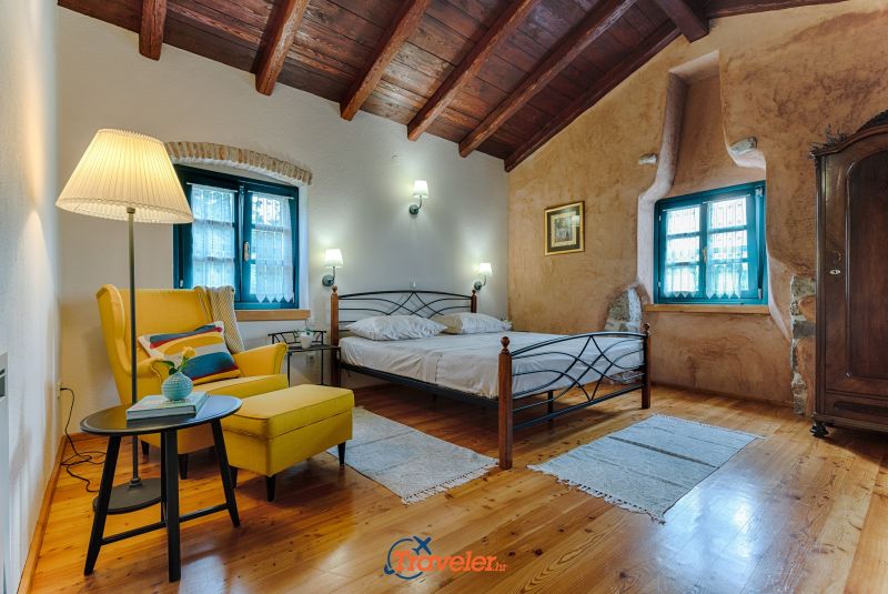Ferienvilla mit Pool in Kroatien, Schlafzimmer mit Doppelbett und gelbem Sessel
