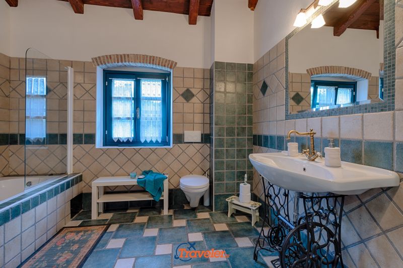 Ferienvilla mit Pool in Kroatien, rustikal eingerichtetes Badezimmer mit weißen und blauen Fliesen, Badewanne, WC und Waschbecken