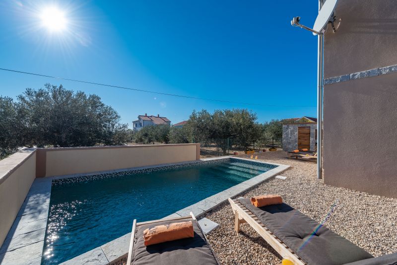 Holiday villa with pool in Croatia, pool with deck chairs and orange towels