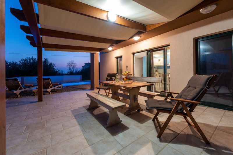 Vila za odmor s bazenom u Hrvatskoj, natkrivena terasa s drvenim stolom i klupom te dvije ležaljke