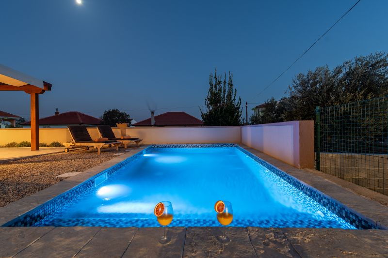 Holiday villa with pool in Croatia, squeezed orange in front of the pool with deck chairs