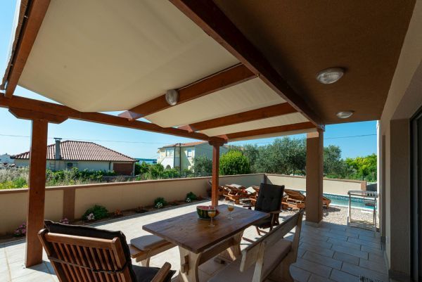 Vila za odmor s bazenom u Hrvatskoj, natkrivena terasa sa drvenim stolom i klupama za blagovanje