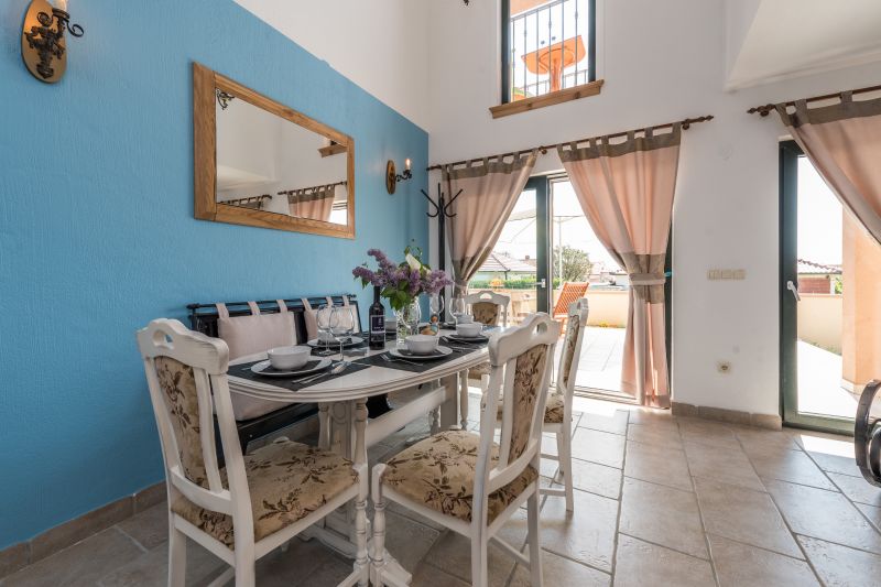 Ferienvilla mit Pool in Kroatien, Tisch und Stühlen zum Essen mit blauer Wand und Spiegel