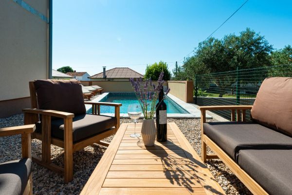 Ferienvilla mit Pool in Kroatien, Holztisch mit Lavendel und Flasche Wein, Poolblick