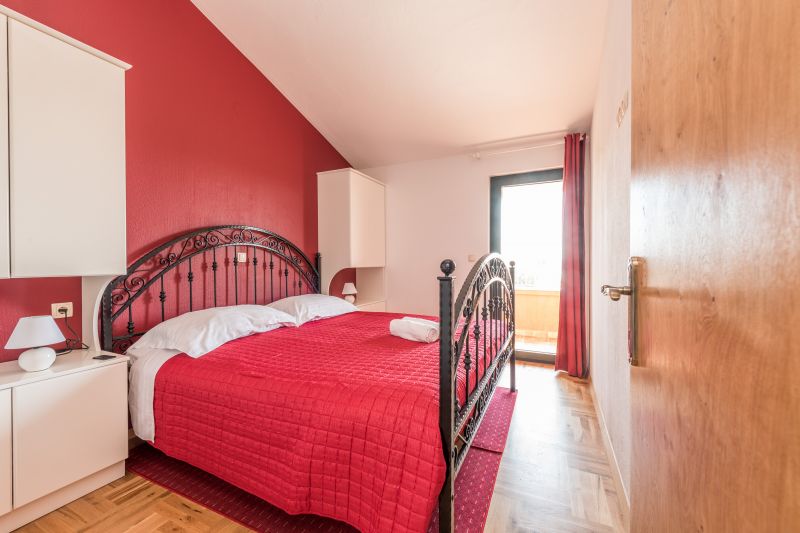 Vila za odmor s bazenom u Hrvatskoj, spavaća soba s krevetom i crvenim zidom