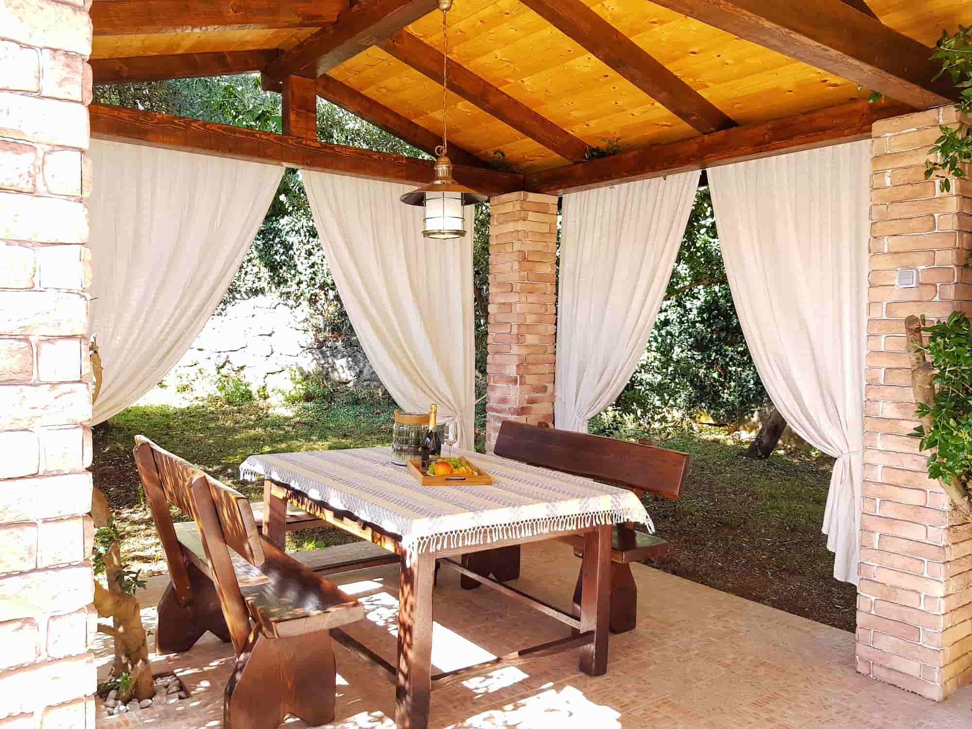 Ferienvilla mit Pool in Kroatien, überdachte Terrasse mit Vordächern und Holztisch und Essbänken